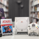 A pile of gaming relics, including the Dreamcast and E.T., sit on a table at the Museum of Video Game History.